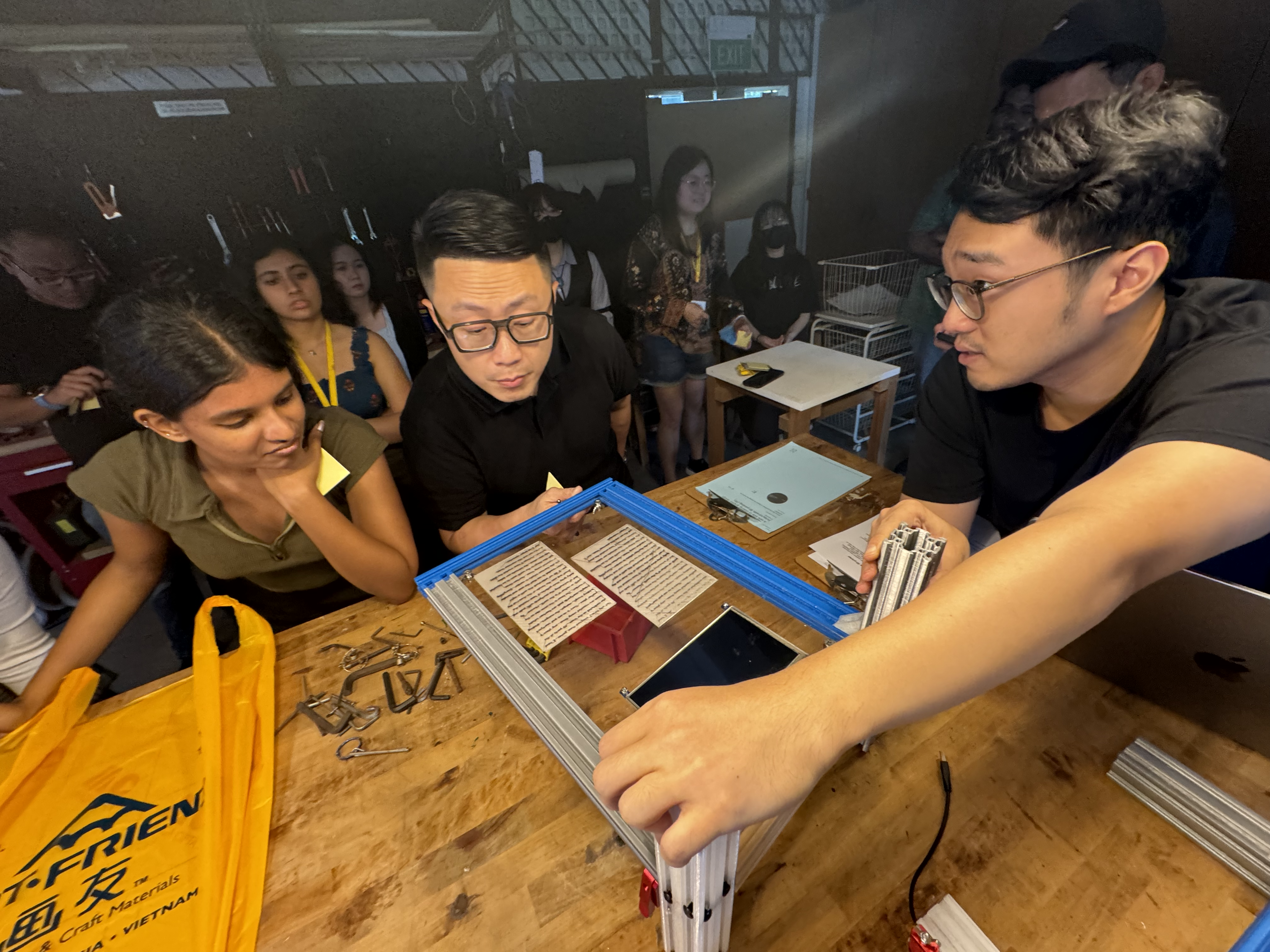 Darius (first from right) discusses his prototype with his classmates (from right) Sheng Jin and xxx during a formative assessment.