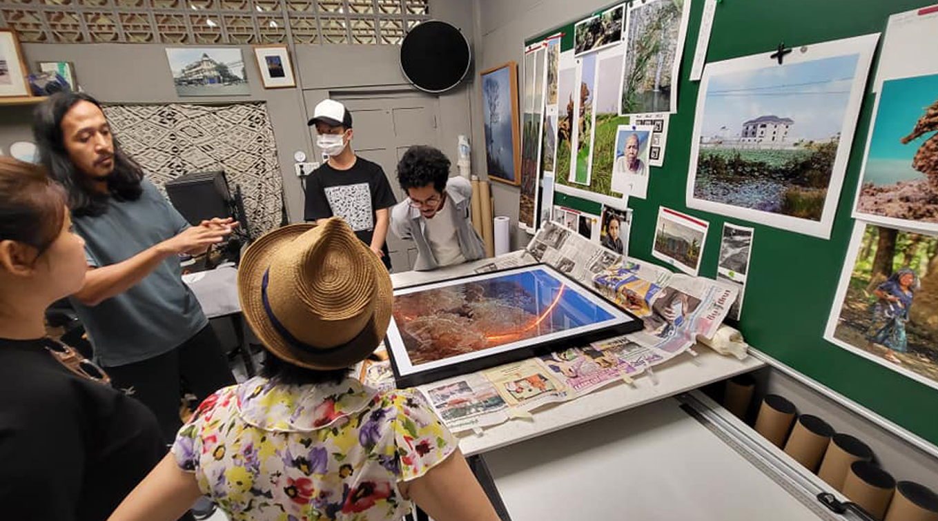 Vanessa and her classmates in the studio of artist Prum Ero, as he walks them through his photographic works of corals.