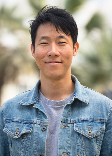 Marcus Yuen profile picture. He wears a denim jacket in front of out of focus palm trees.