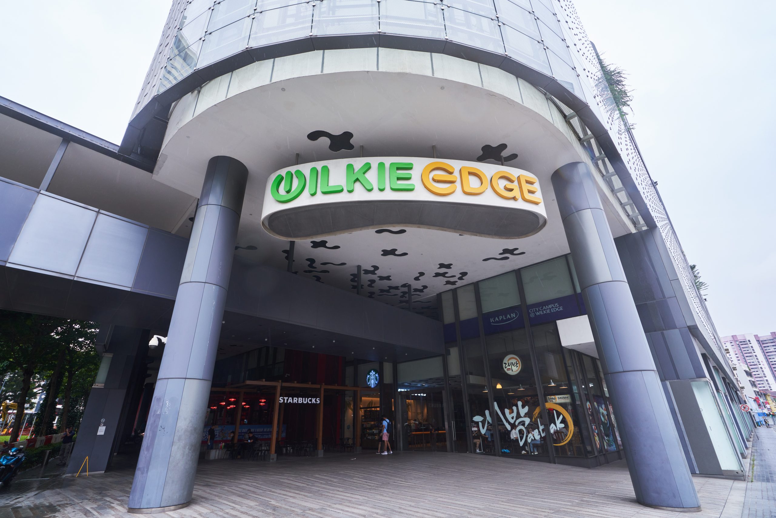 Main entrance of Wilkie Edge with its curved signage, patterned ceiling and shopfront eateries.