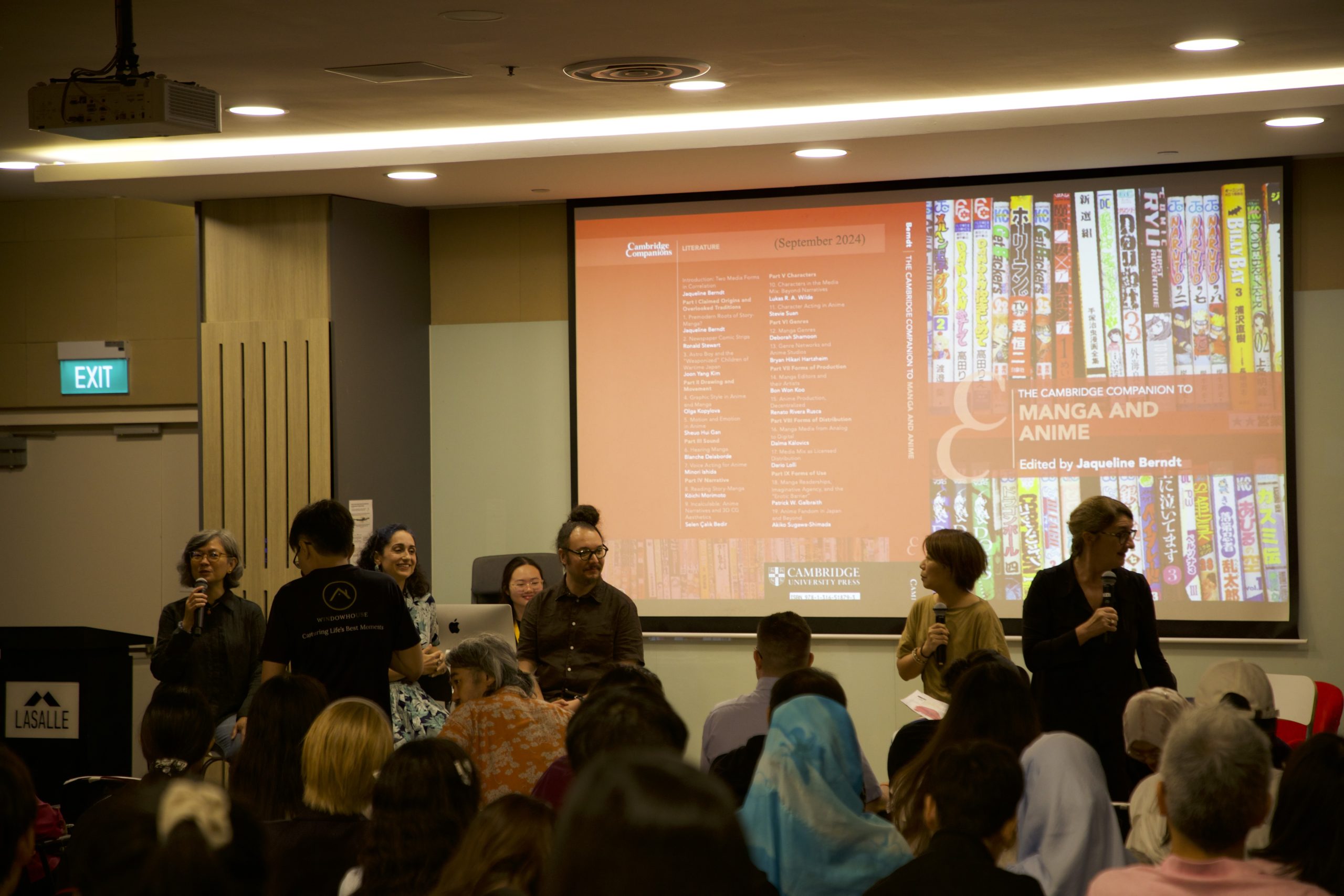 LASALLE lecture hall event with speakers discussing manga and anime, as a presentation slide is projected to a full audience.