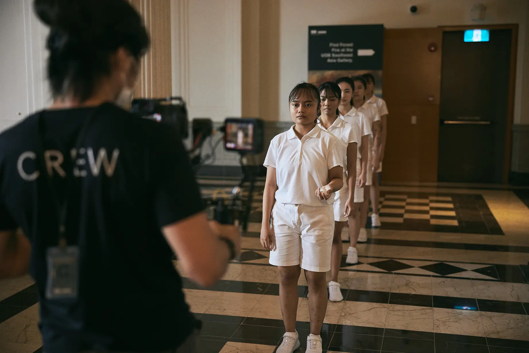 Dancers stand in a line as crew set up the film shot.